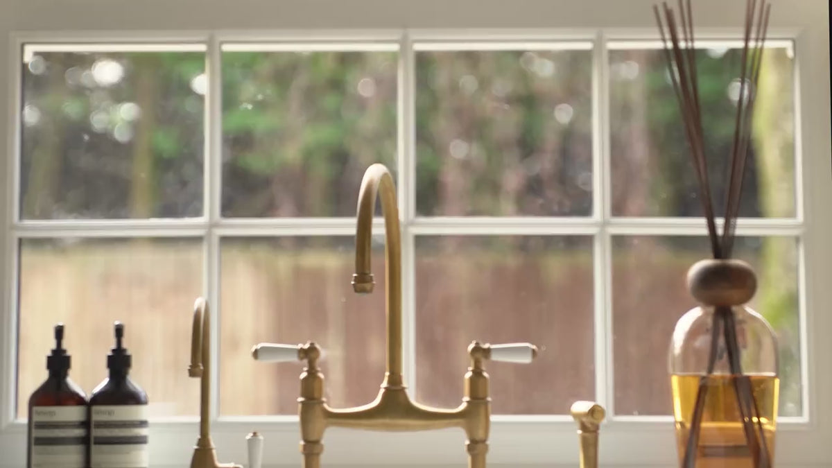A brass tap and reed diffuser at a kitchen window